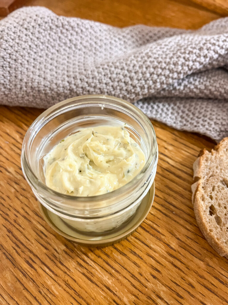 whipped brown butter herb spread in a quilted mason jar on a wooden table with a gray towel