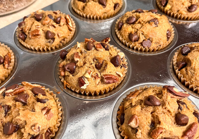 banana bread muffins with chocolate chips and pecans in a stainless steel muffin pan