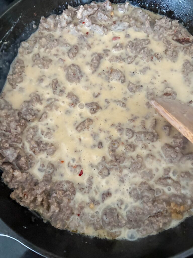 southern sausage gravy in a cast iron skillet with a wooden spoon