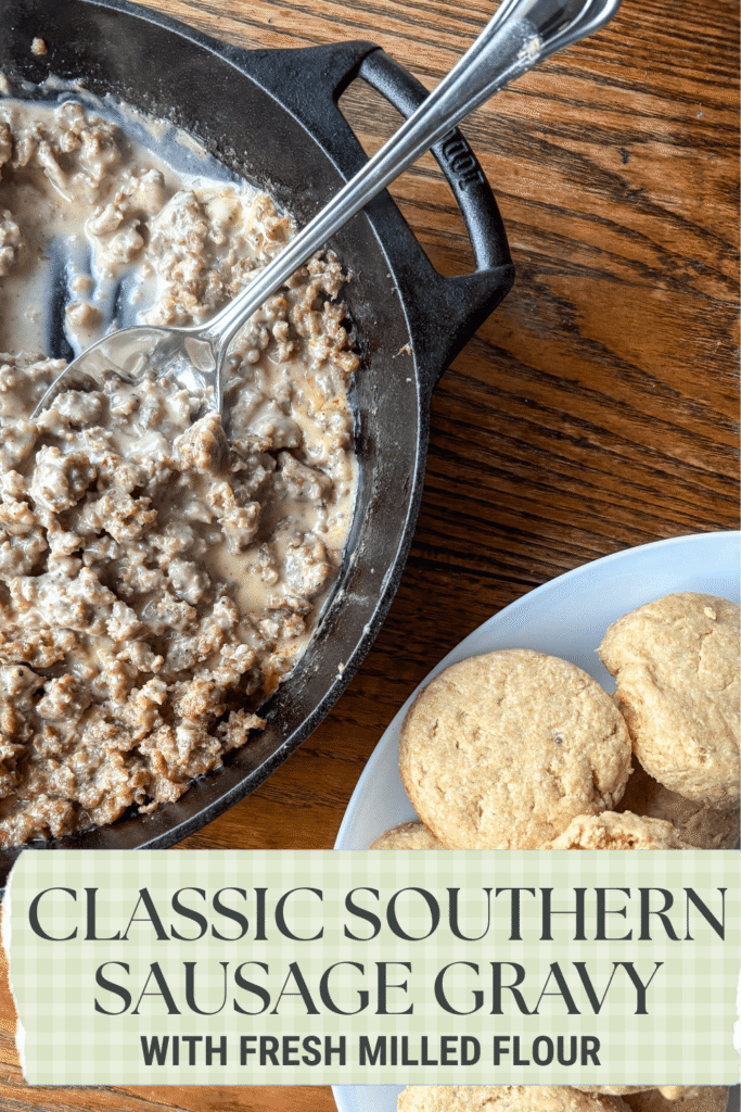 cast iron skillet with southern sausage gravy on a kitchen table beside a plate with biscuits on it