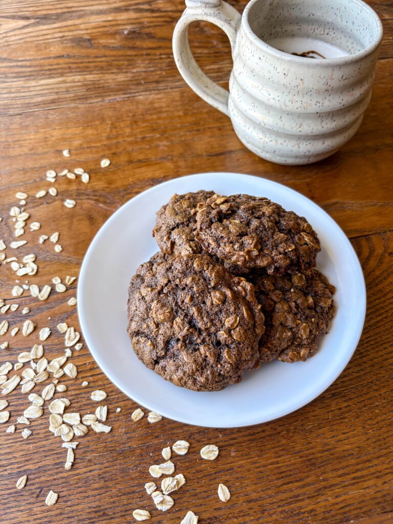 blackstrap molasses oatmeal cookies on a plate with a mug and oats on a kitchen table