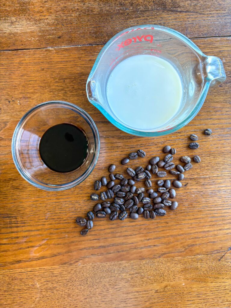 blackstrap molasses in a glass bowl with measuring cup of whole milk and coffee beans on a kitchen table