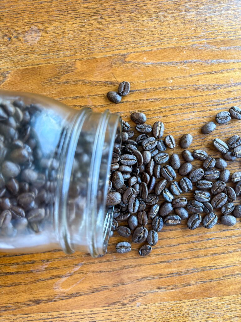 coffee beans spilling out of a mason jar onto a kitchen table