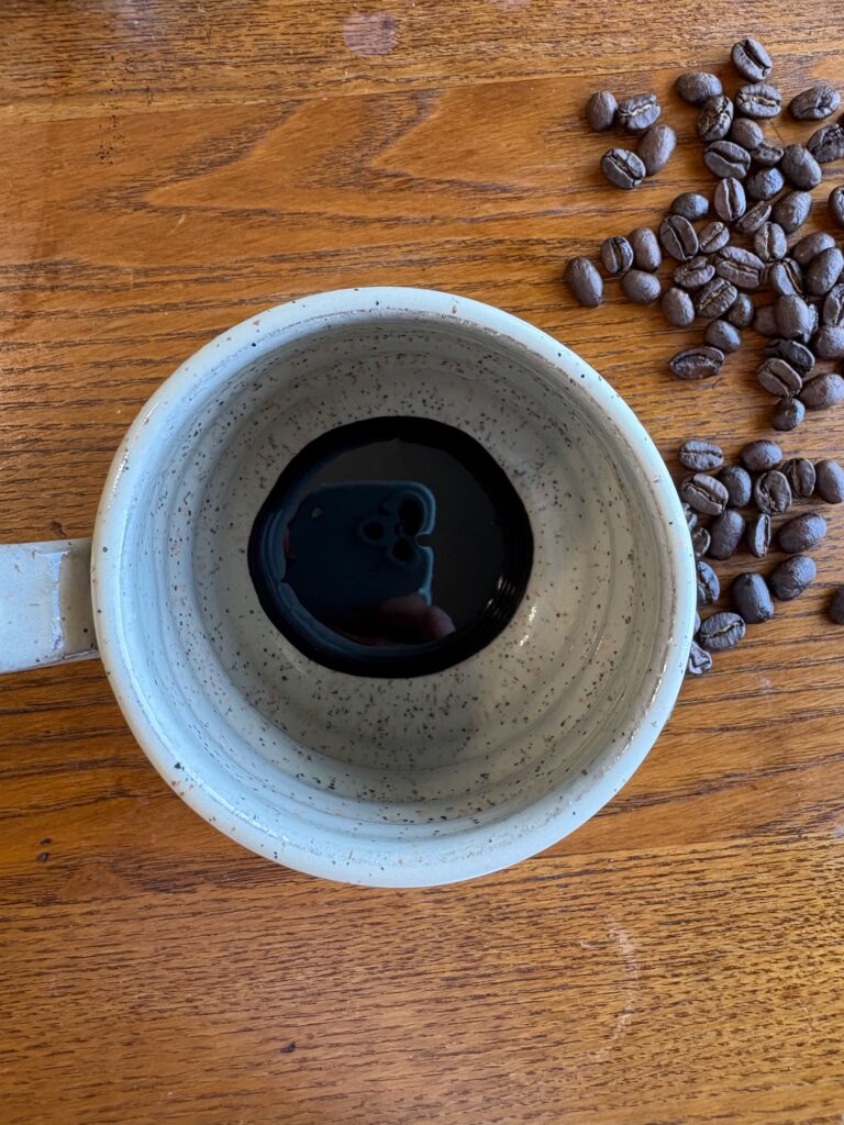 blackstrap molasses in a mug on a kitchen table with coffee beans