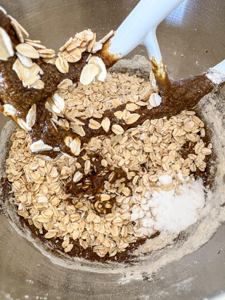 bowl with oats, baking powder and molasses and butter with a paddle attachment in a stand mixer
