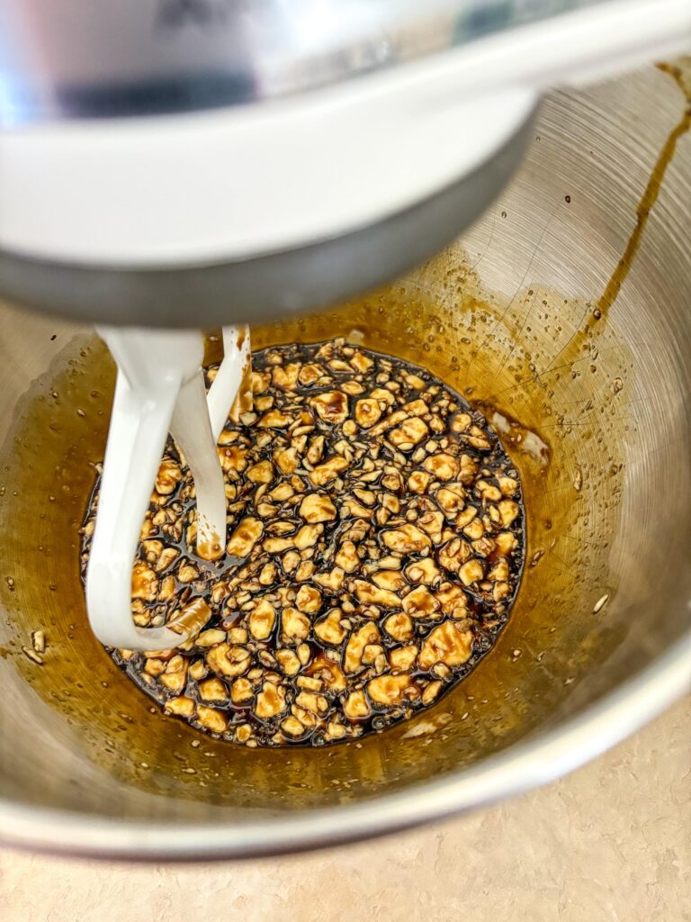 stand mixer bowl with little clumps of butter and molasses with a paddle attachment