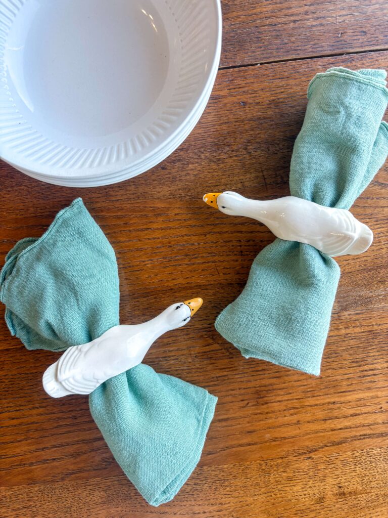 antique white bowl on a kitchen table with green napkins and thrifted napkin rings