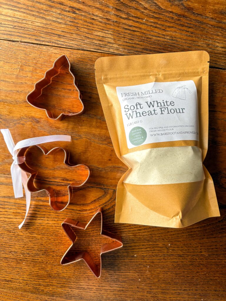bag of fresh milled soft white wheat flour on a kitchen table with vintage Christmas cookie cutters