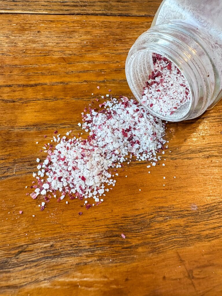 handmade herb salt spilling out of a jar onto a kitchen table